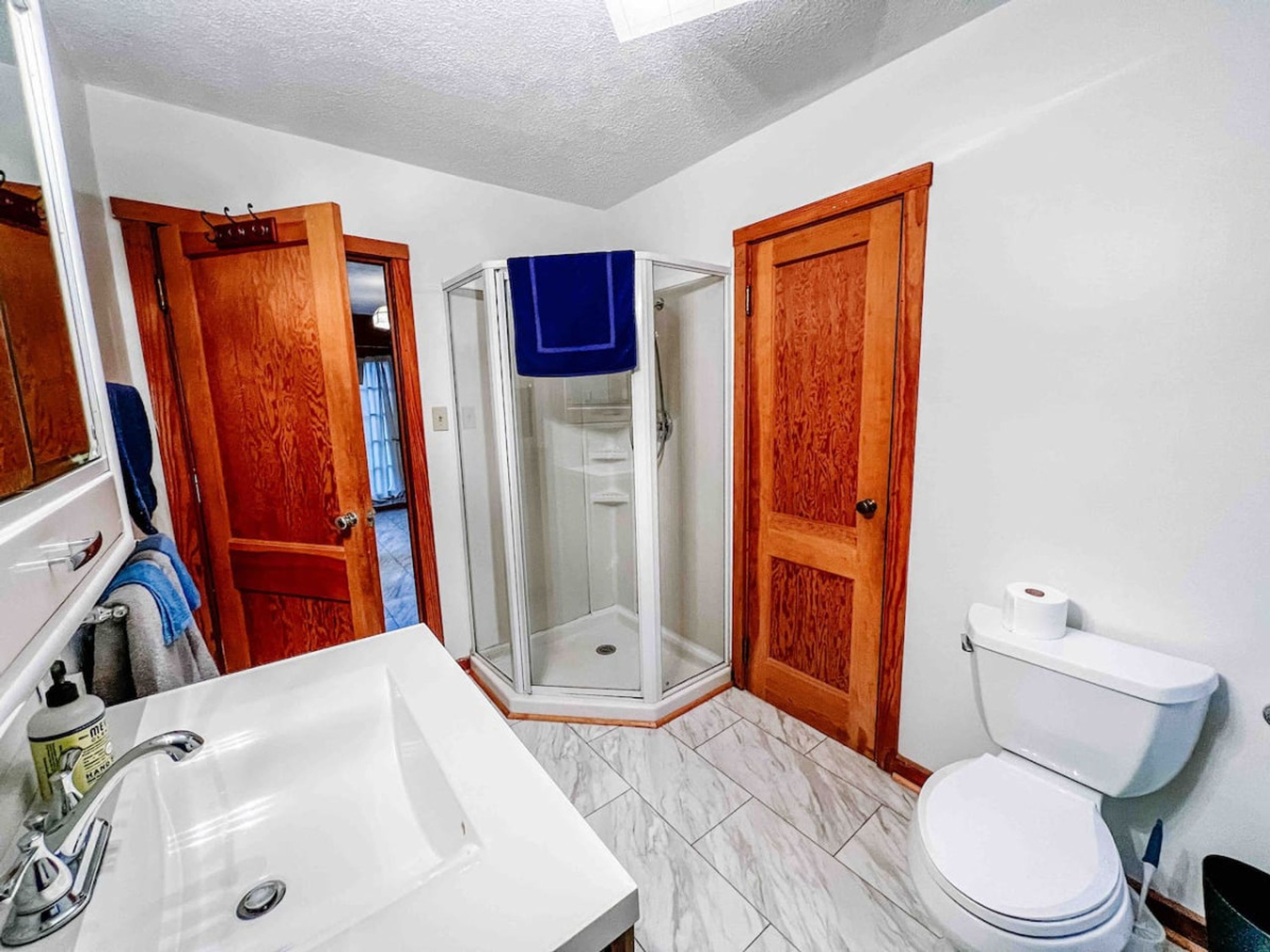 A bathroom with a white sink, a toilet, and a glass shower enclosure.