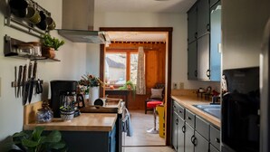 Une cuisine dotée d’un plan de travail en bois, de couteaux suspendus, d’une machine à café et donnant sur un coin repas.