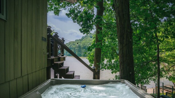 Un bain à remous avec vue sur une rivière et une forêt.
