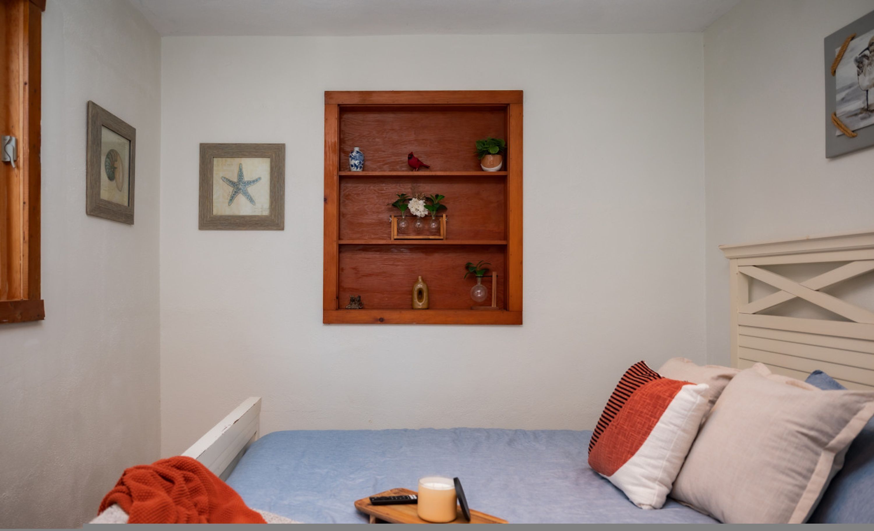 Ein Schlafzimmer mit einem Bett, einer Holzhilfe mit Dekoration und gerahmten Bildern an der Wand.