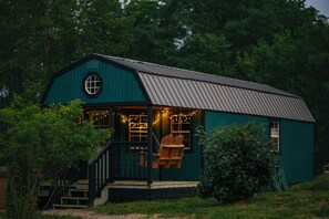 A small, single-story building with a porch, a swing chair, and string lights. - Farm Stay Hot tub Pond Nature Views Near Dwntwn (Indianapolis)