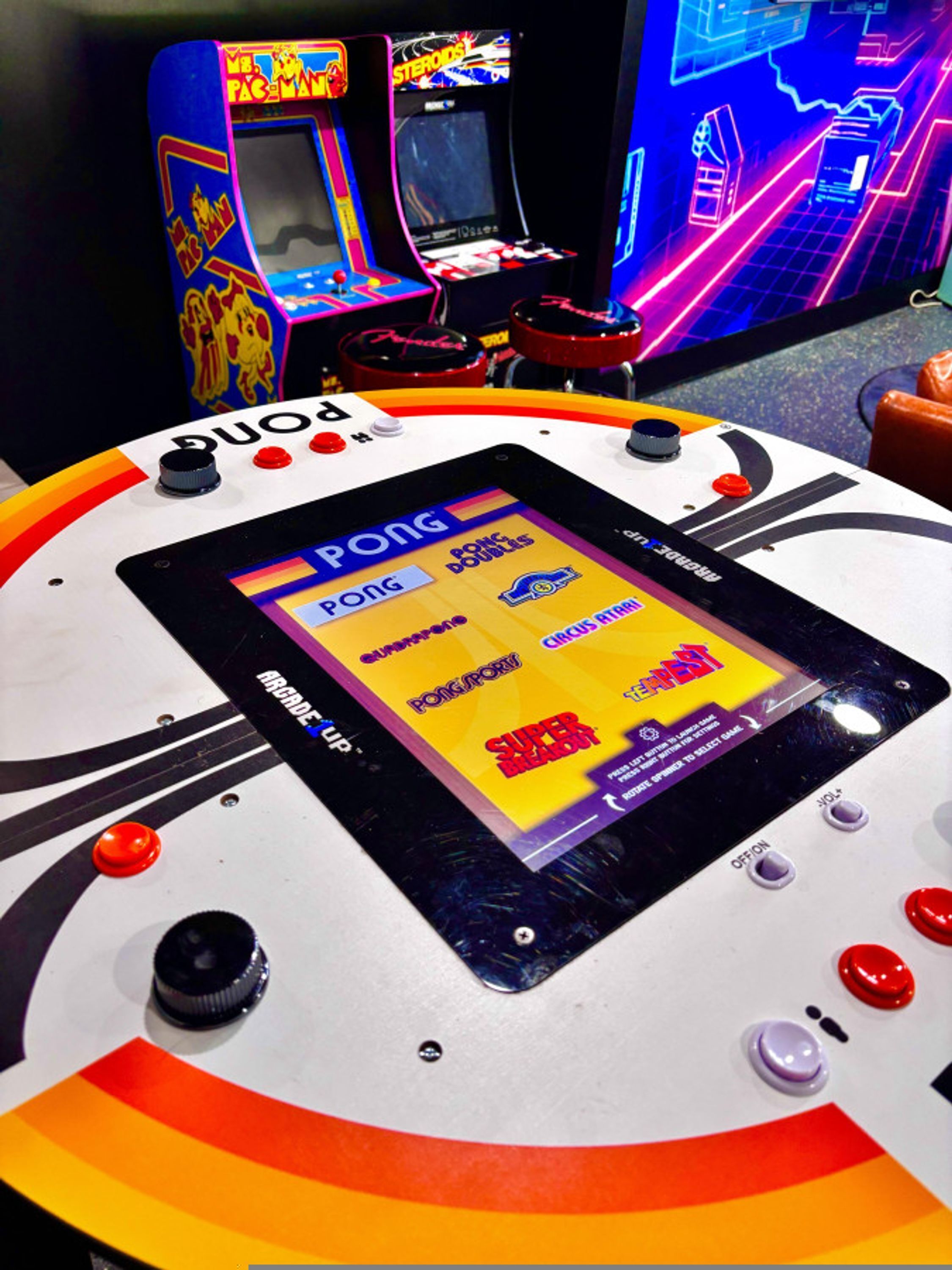 Una máquina de videojuegos Pong con una interfaz colorida y varios botones de control.