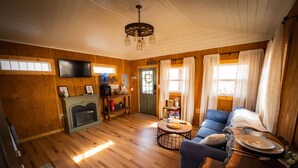 Un interior de madera acogedor con chimenea, televisor y comedor.