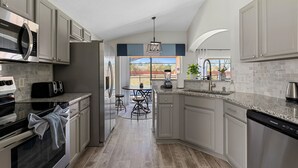 A modern kitchen with stainless steel appliances, a granite countertop, and a view to the outdoors.