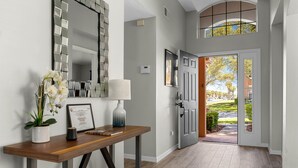 A hallway with a wooden console table, a mirror, and a door leading to a garden.
