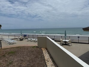 Un patio frente a la playa con sillas de descanso y sombrillas, con vista al océano.