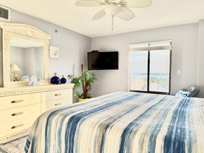 Un dormitorio con una cama grande, un aparador, un espejo, un televisor y una ventana con vistas.