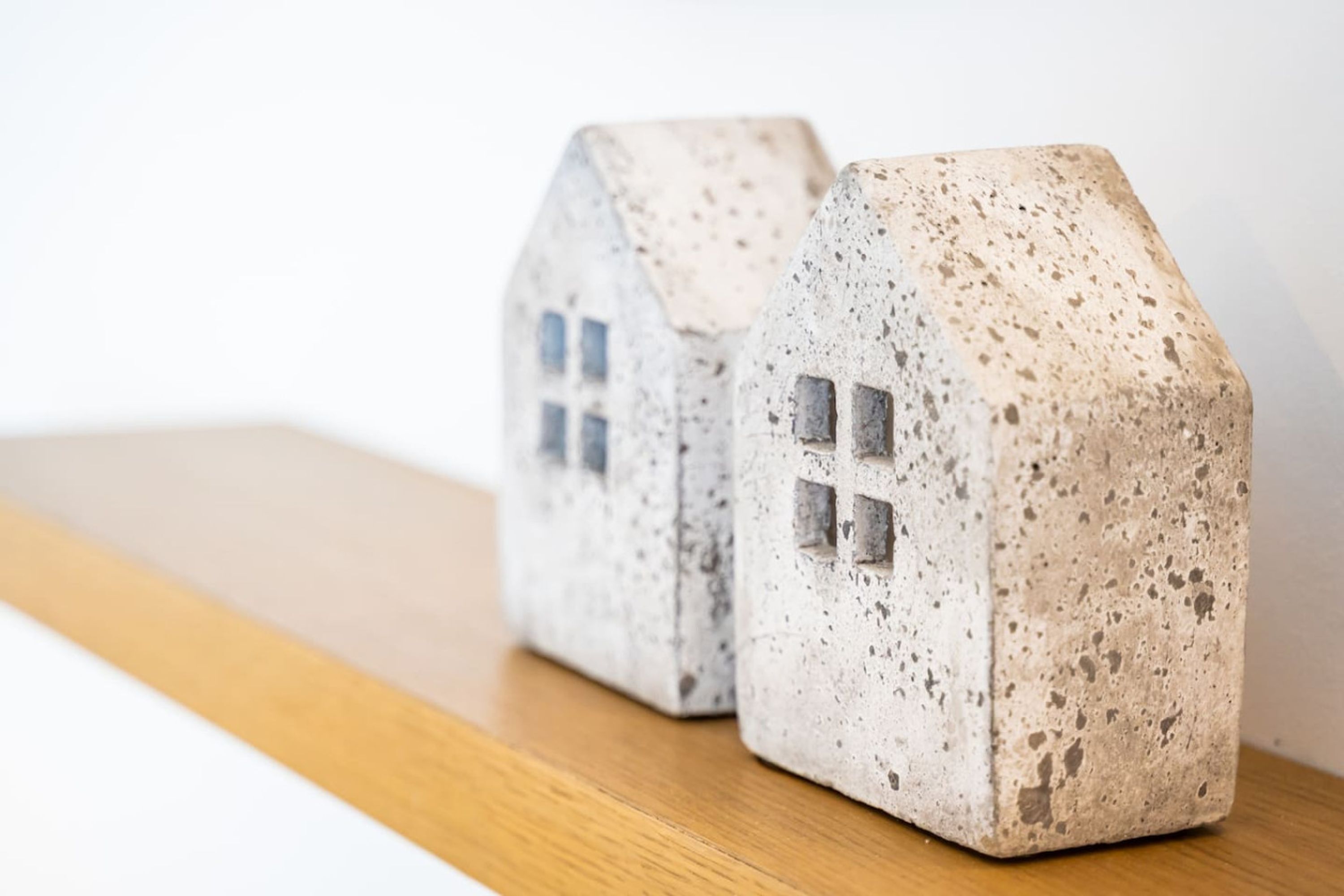Dos pequeñas figuras con forma de casa y textura interesante sobre una superficie de madera.