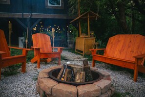 Een gezellig buitengebied met houten Adirondack stoelen en een vuurkorf.