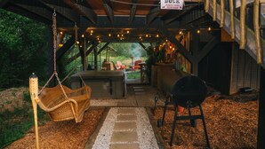 Una terraza de madera al aire libre con una silla colgante, una parrilla para barbacoa y un letrero que dice "DOCK PLEASE MIND YOUR HEAD".
