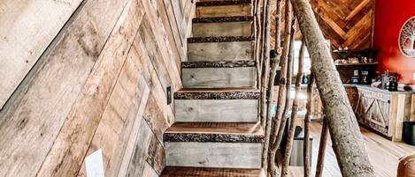 A wooden staircase with a metal railing, surrounded by wooden walls and beams.
