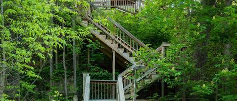 A wooden staircase leading to a dock with kayaks and a boat.