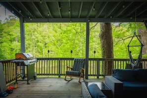 A covered outdoor area with a wooden deck, a rocking chair, a hammock, and a grill. - Lakefront-nestled in Nirvana (Martinsville)
