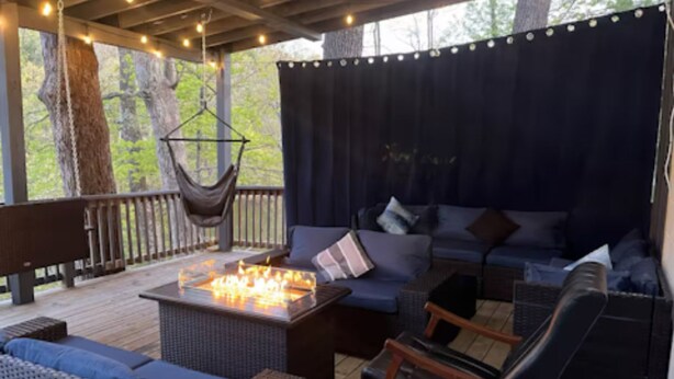 A covered outdoor seating area with a fire feature, cushioned seating, and a hanging chair. - Lakefront-nestled in Nirvana (Martinsville)
