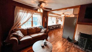 A cozy living room with a brown leather sofa, a round coffee table, and a fireplace.