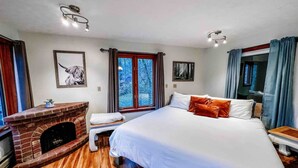 A bedroom with a large bed, a fireplace, and a window with a view of trees. - Two Lakefront Cabins Next Door (Martinsville)