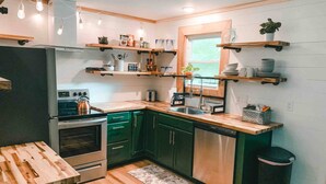 A compact kitchen with wooden cabinets, a built-in oven, a sink, and a window. - Two Lakefront Cabins Next Door (Martinsville)