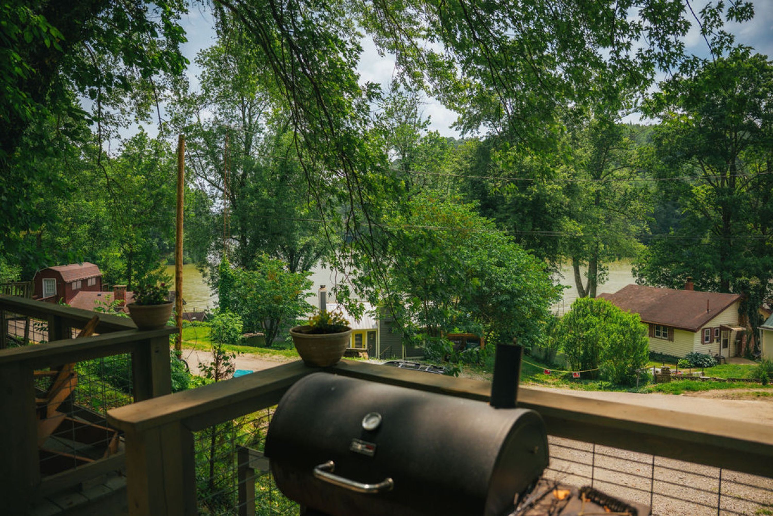 Ein Balkon mit Grill, der auf ein Wohngebiet mit Häusern und Grünflächen blickt.