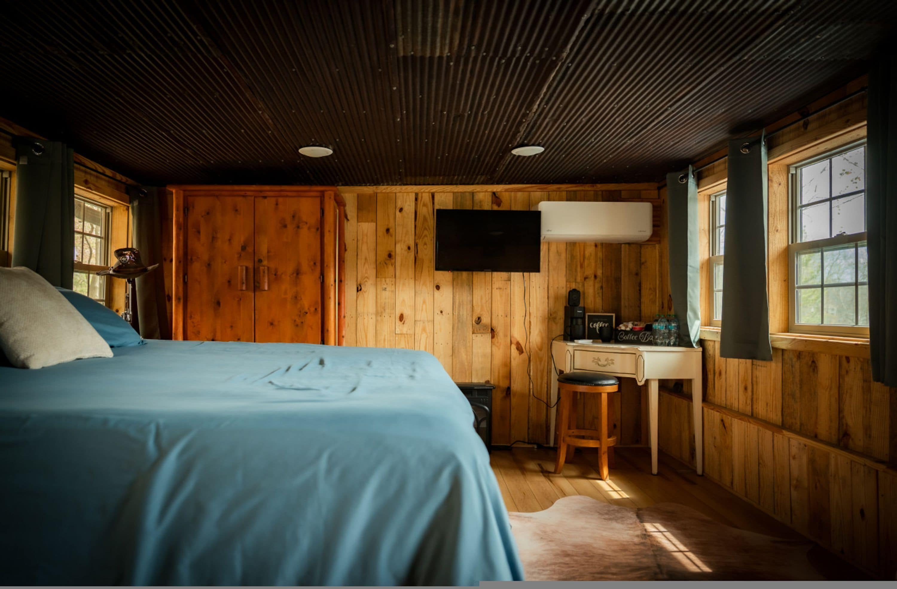 Een kamer met houten lambrisering, een bed, een bureau en een televisie.