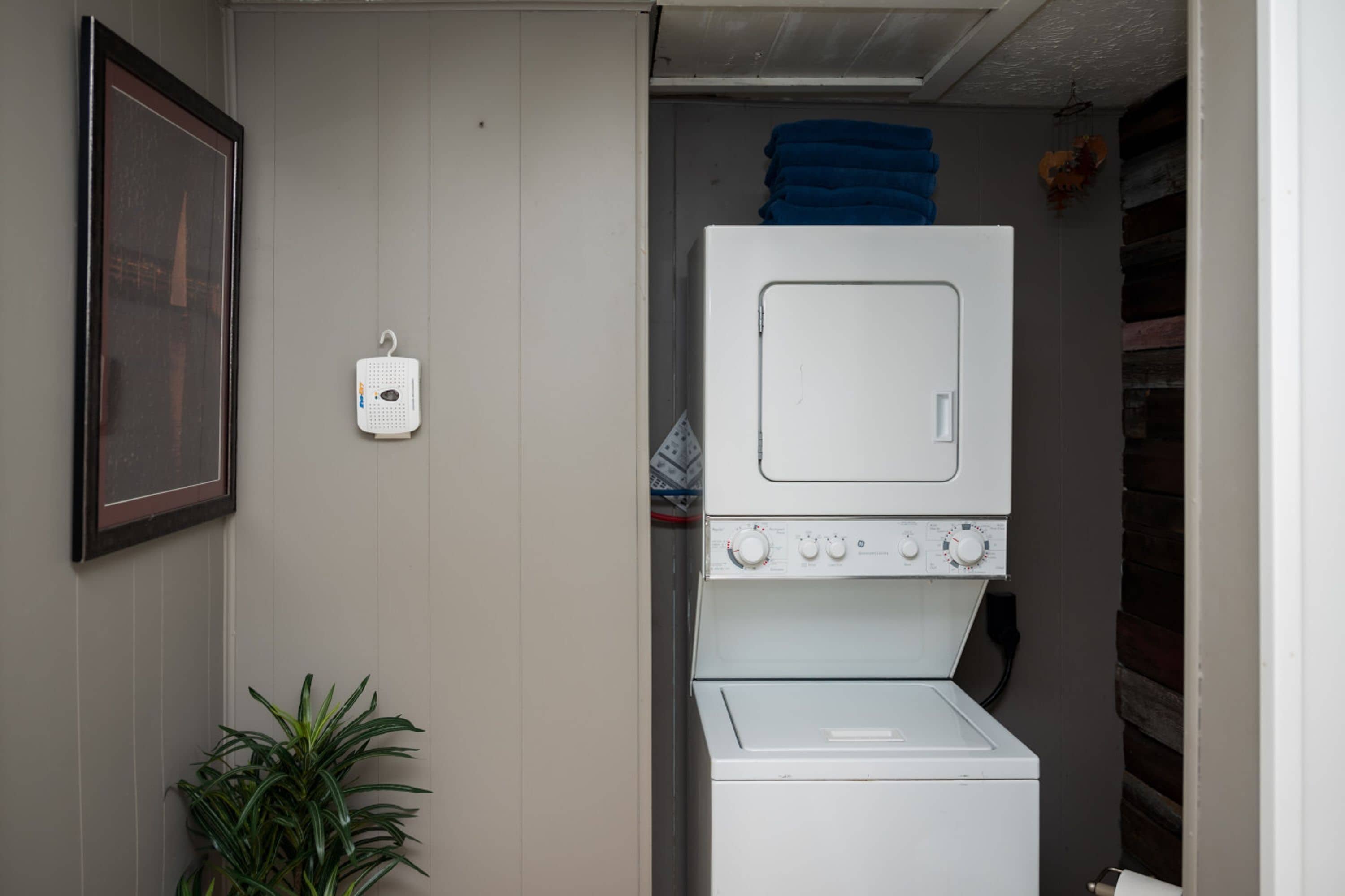 Een wasruimte met een wasmachine en droger boven elkaar geplaatst.