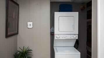 Een wasruimte met een wasmachine en droger boven elkaar geplaatst.