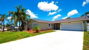 A single-story house with a garage, surrounded by a well-maintained lawn and palm trees. - Fun Pool Relax16miles Bushgarden (Tampa)
