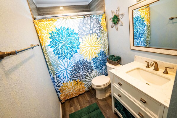A bathroom with a toilet, sink, and shower curtain with a floral pattern. - Fun Pool Relax16miles Bushgarden (Tampa)