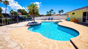 A swimming pool with a curved design, surrounded by a paved patio and palm trees. - Fun Pool Relax16miles Bushgarden (Tampa)