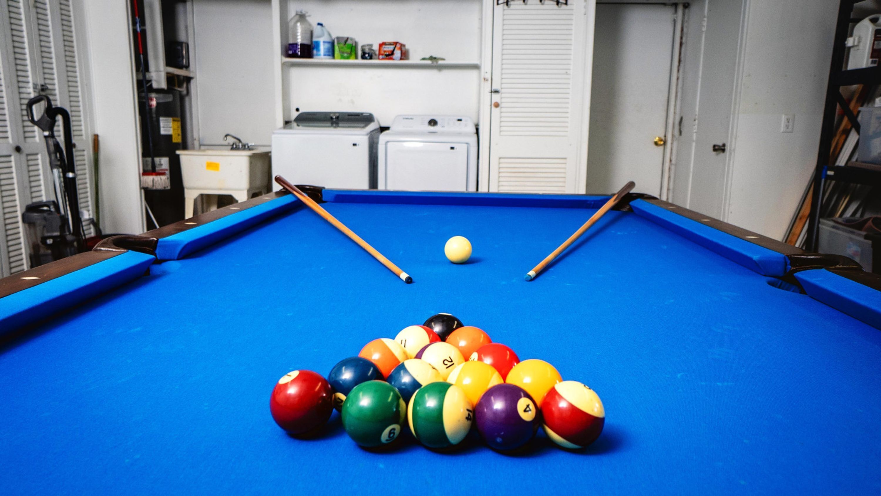 A pool table with a set of billiard balls and two pool cues.