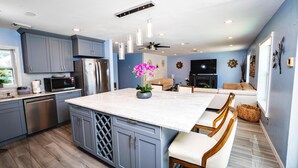 A modern kitchen with grey cabinets, stainless steel appliances, and a marble island with a potted orchid. - Fun Pool Relax16miles Bushgarden (Tampa)