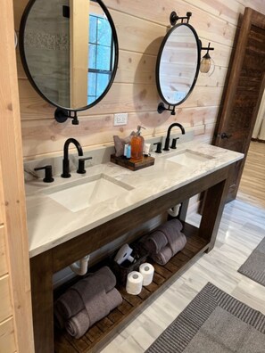 Un baño con dos lavamanos, tocador de madera y un espejo sobre cada lavamanos.