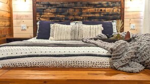 A cozy bedroom with a wooden headboard, a bed with patterned bedding, and a decorative wall. - Lofted Pines Hot Tub Arcade Air Hockey (Broken Bow)