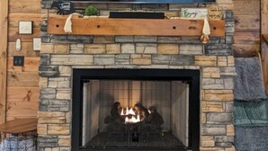 A stone fireplace with a flat-screen TV mounted above it displaying the Netflix logo. - Lofted Pines Hot Tub Arcade Air Hockey (Broken Bow)