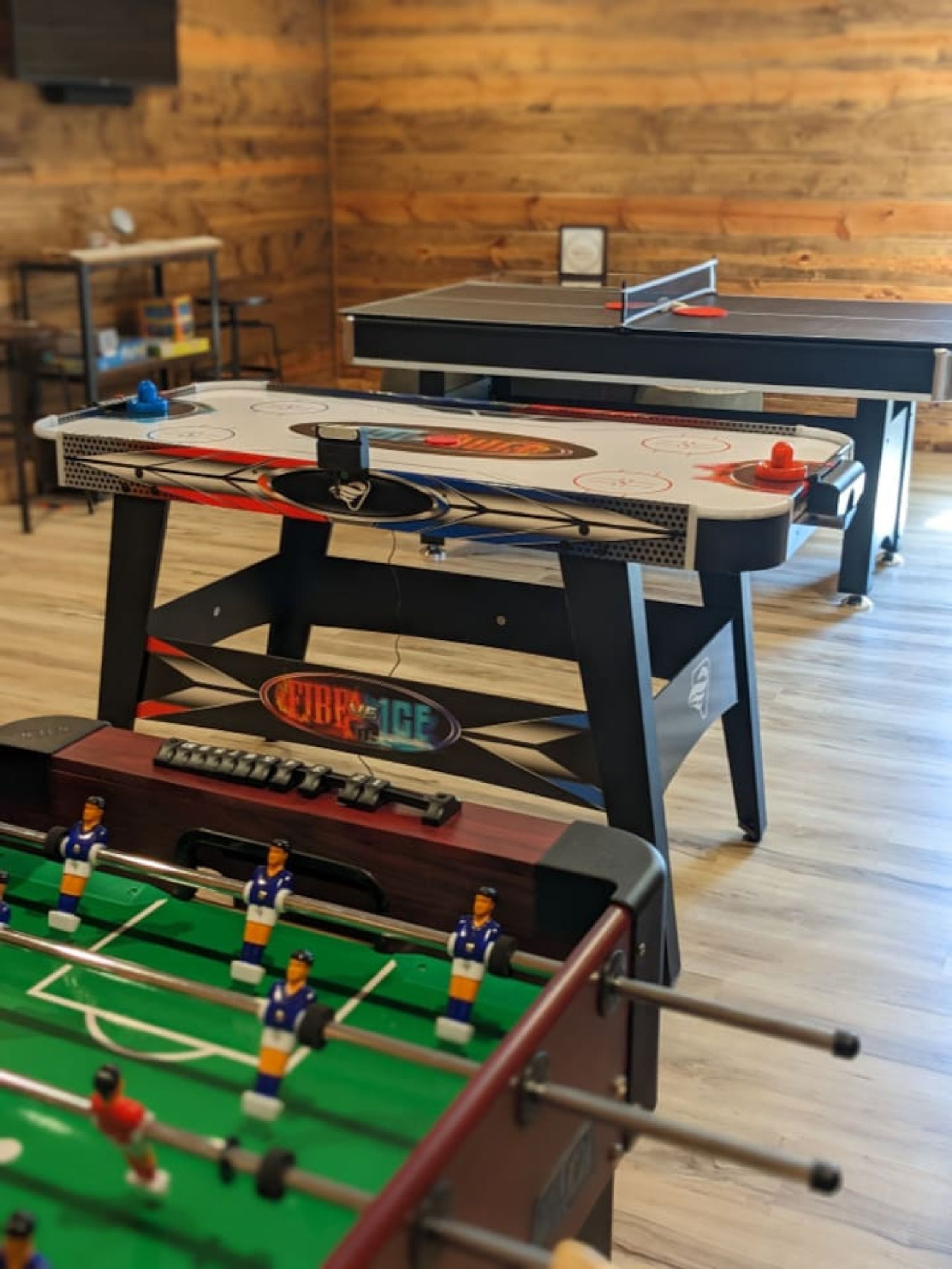 Una habitación con dos mesas de futbolín y una mesa de futbolín en primer plano.
