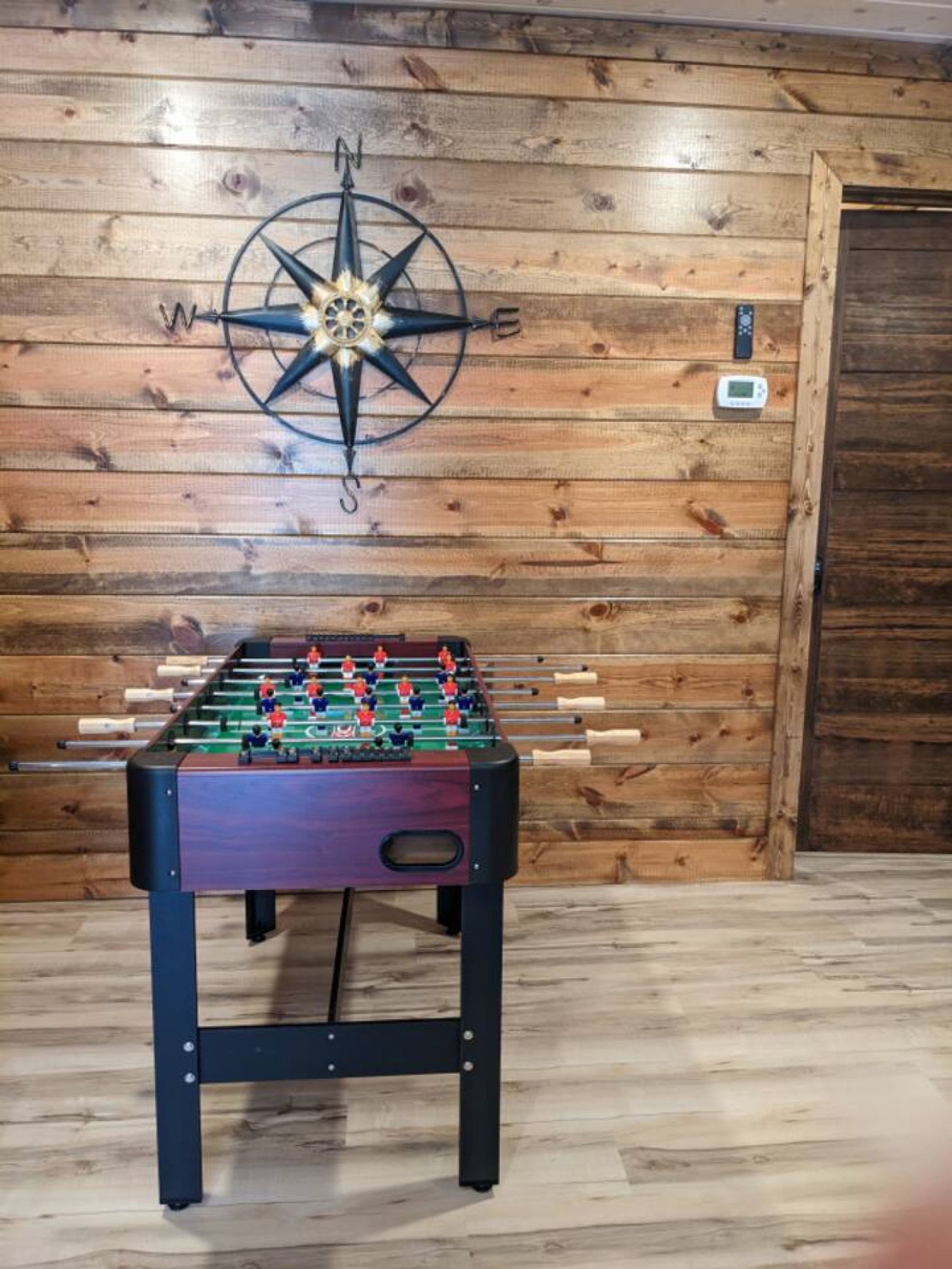 Una mesa de fútbol de mesa en una habitación con paredes y puerta de madera.