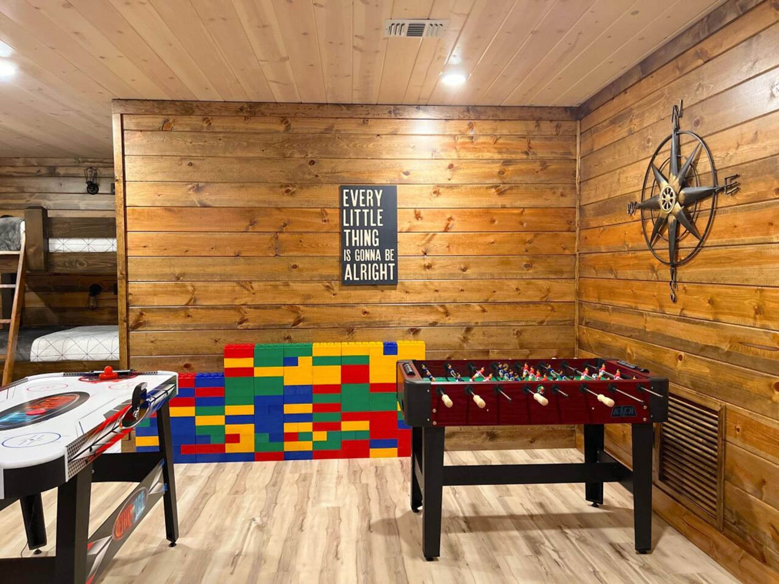 Una habitación acogedora con paredes de madera, una mesa de futbolín, una mesa de ping pong y una cita motivacional en la pared.