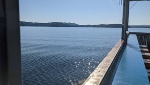A view from a balcony overlooking calm water with distant hills. - Lofted Pines Hot Tub Arcade Air Hockey (Broken Bow)