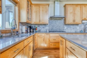 Una cucina con mobili in legno, un piano di lavoro in granito e una parete rivestita di piastrelle.