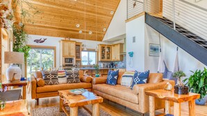A spacious living area with a wooden ceiling, a sofa set, a coffee table, and a staircase.