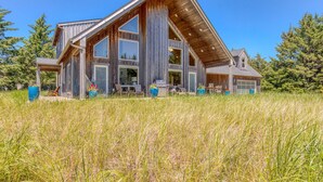 A large, modern log cabin with multiple large windows and a spacious porch area.