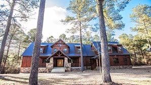 A rustic cabin with a stone foundation, wooden exterior, and a steeply pitched roof.