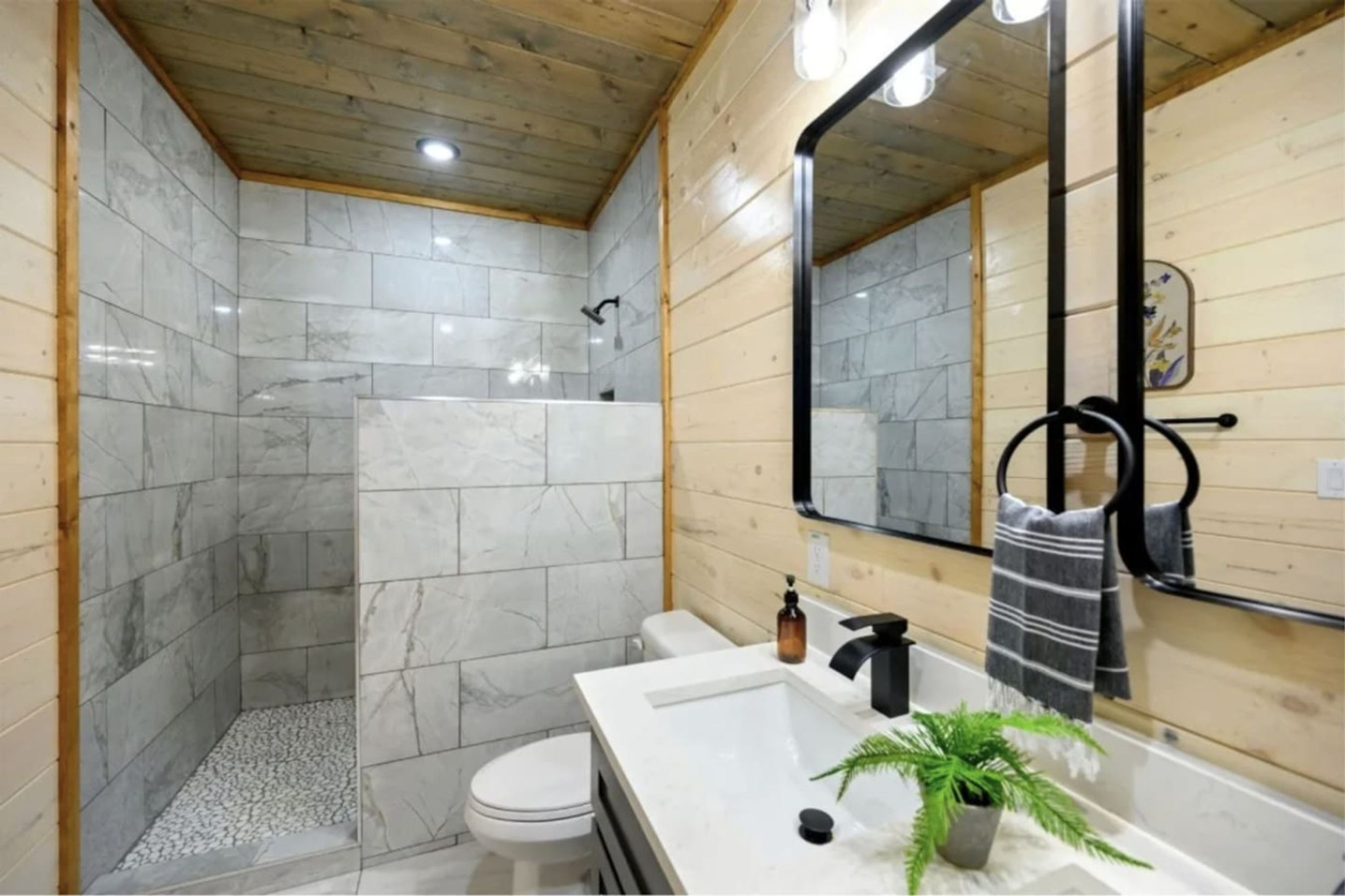 Een moderne badkamer met douche, toilet en wastafel.