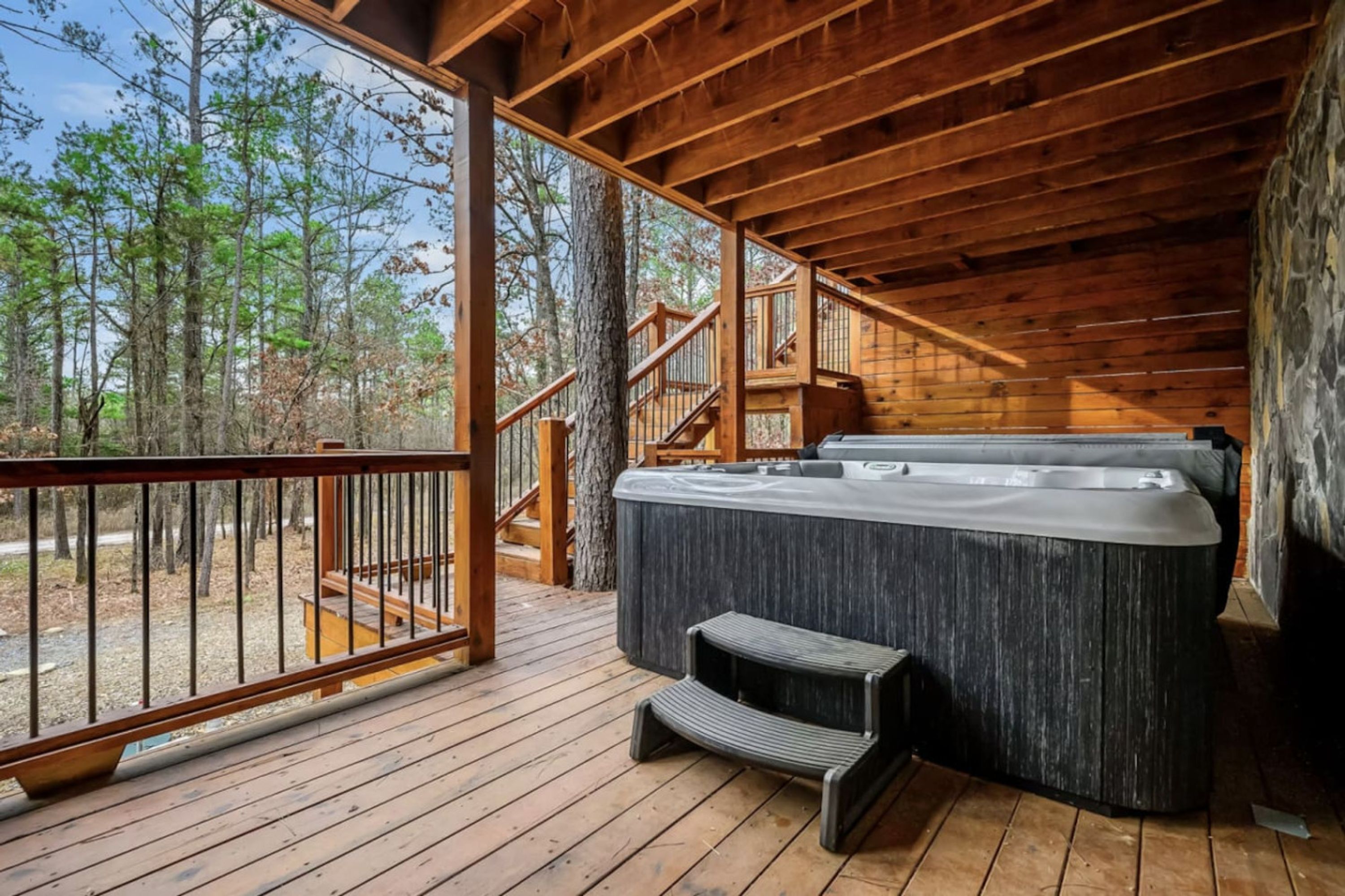 Une terrasse en bois avec un jacuzzi, des marches et un escalier menant à un niveau supérieur.