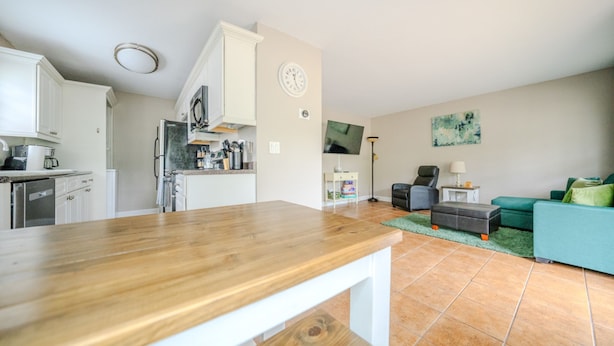A modern kitchen with white cabinets, a wooden countertop, and a dining area with a table. - Convenient to Ole Miss The Square (Oxford)