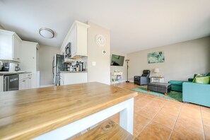 Een moderne keuken met witte kasten, een houten aanrechtblad en een eethoek met een tafel.