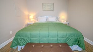 A bedroom with a green bedspread, two bedside lamps, a framed quote on the wall, and a wooden bench at the foot of the bed. - Convenient to Ole Miss The Square (Oxford)