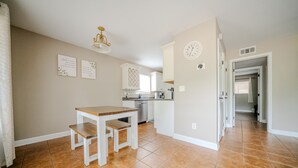 A kitchen with a dining table and bench, a clock on the wall, and a kitchen island. - Convenient to Ole Miss The Square (Oxford)