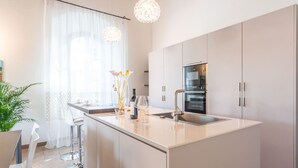 Ett modernt kök med en central köksö, rostfria vitvaror och hängande lampor.
