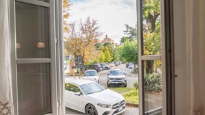 En vy genom ett fönster ut över en parkeringsplats med flera bilar, inklusive en vit bil i förgrunden.