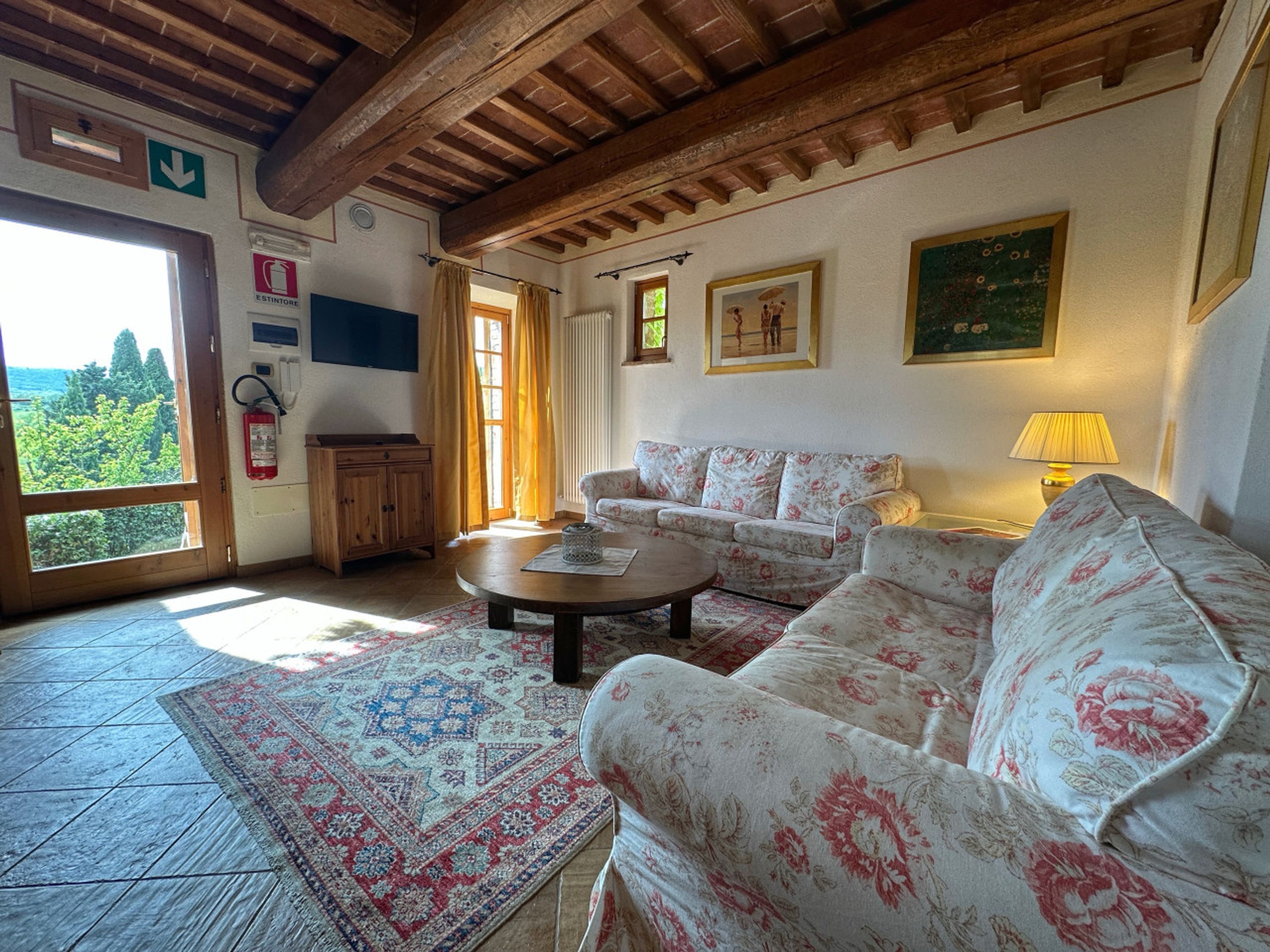 A cozy living room with a wooden ceiling, a sofa, a coffee table, and a patterned rug.